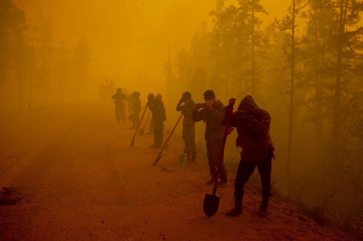 Volunteers pause while working at the scene of a forest fire near Kyuyorelyakh village at Gorny Ulus area west of Yakutsk, in Russia, on Aug. 7, 2021. (Ivan Nikiforov/AP Photo)