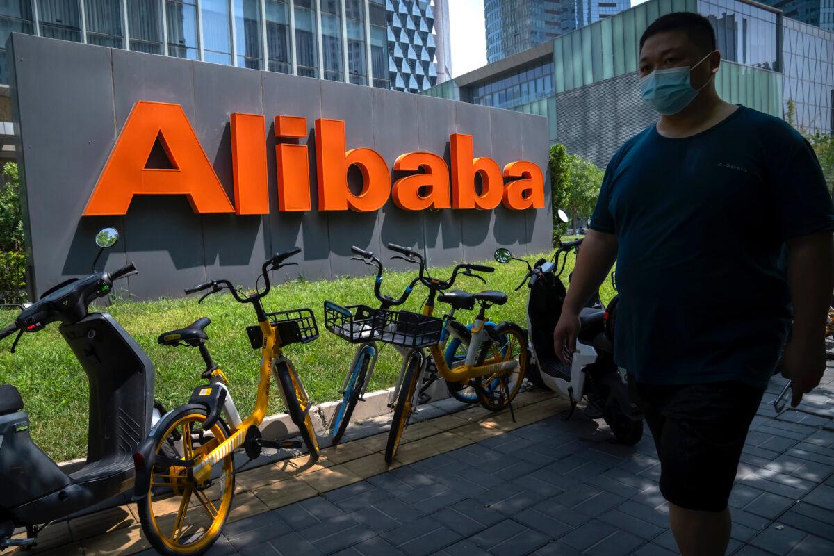 A man wearing a face mask walks past the offices of the Chinese e-commerce firm Alibaba in Beijing on Aug. 10, 2021. (AP Photo/Mark Schiefelbein)