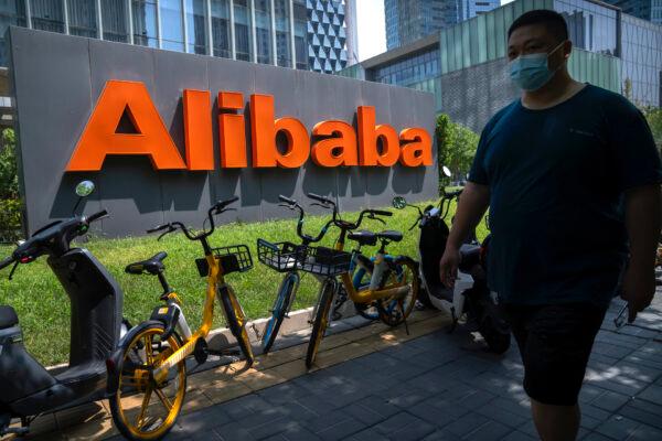 A man wearing a face mask walks past the offices of Chinese e-commerce firm Alibaba in Beijing, on Aug. 10, 2021. (AP Photo/Mark Schiefelbein)