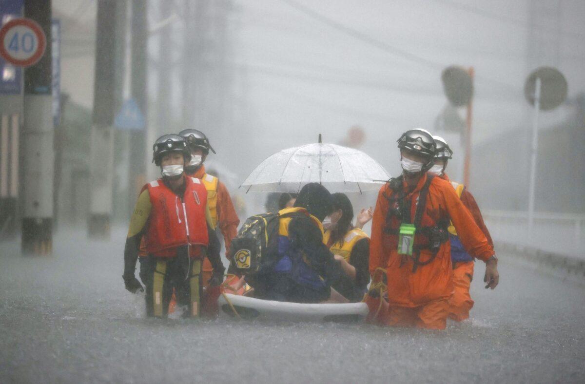 Firefighters transport stranded residents on a boat in a road flooded by heavy rain in Kurume, Fukuoka prefecture, western Japan, on Aug. 14, 2021. (Kyodo/via Reuters)
