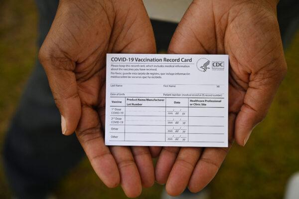 A health care worker displays a COVID-19 Vaccination Record Card during a vaccine and health clinic at QueensCare Health Center in a predominantly Latino neighborhood in Los Angeles, on Aug. 11, 2021. (Robyn Beck/AFP via Getty Images)