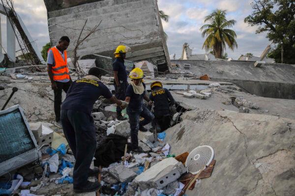Firefighters search for survivors inside a collapsed building, after the Aug. 14 7.2 magnitude earthquake in Les Cayes, Haiti, on Aug. 15, 2021. (Joseph Odelyn/AP Photo)