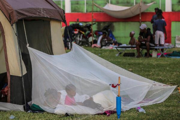 A family wakes inside a mosquito net outside a tent after spending the night at a soccer field following a 7.2 magnitude earthquake in Les Cayes, Haiti, on Aug. 15, 2021. (Joseph Odelyn/AP Photo)