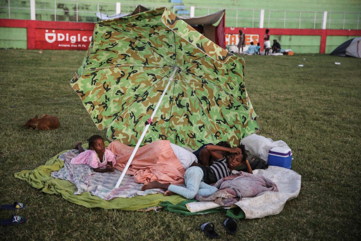 People rest after spending the night at a soccer field following the 7.2 magnitude earthquake in Les Cayes, Haiti, on Aug. 15, 2021. (Joseph Odelyn/AP Photo)