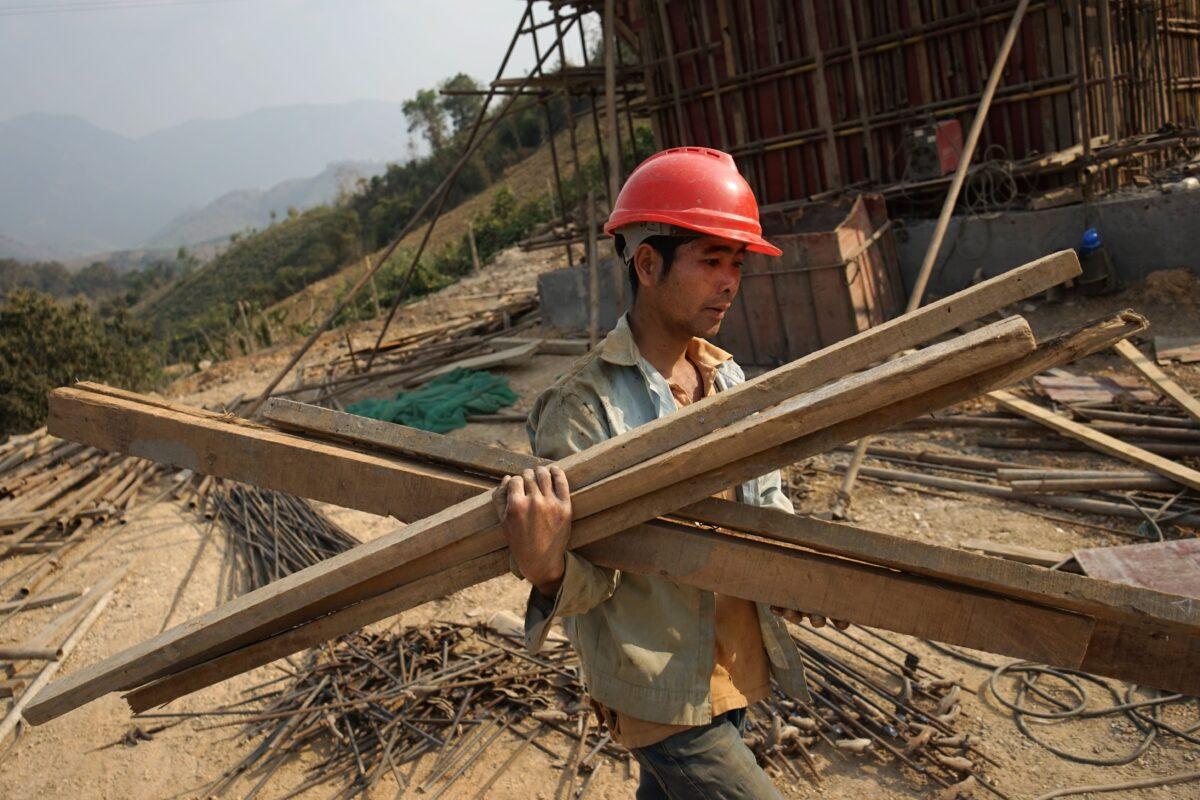 A Chinese worker carries materials for the first rail line linking China to Laos, a key part of Beijing's "Belt and Road" project across the Mekong River in Luang Prabang, Laos, on Feb. 8, 2020. (Aidan Jones/AFP via Getty Images)