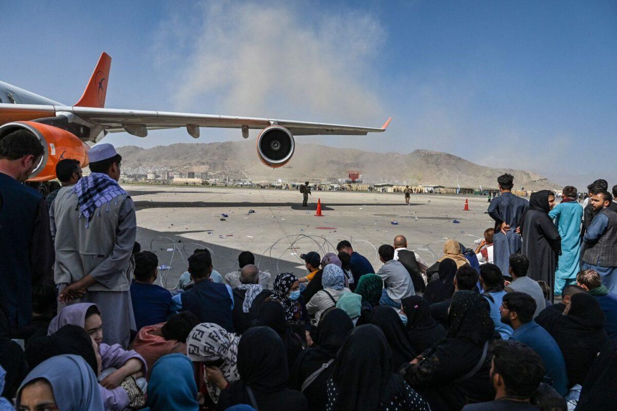 Afghan people sit as they wait to leave the Kabul airport in Kabul on Aug. 16, 2021, after a stunningly swift end to Afghanistan's 20-year war. (Wakil Kahsar/AFP via Getty Images)