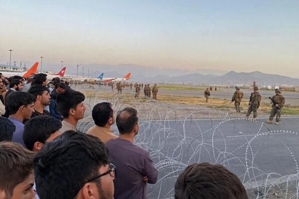 Afghans (L) crowd at the airport in Kabul as U.S. soldiers stand guard on Aug. 16, 2021. (SHAKIB RAHMANI/AFP via Getty Images)