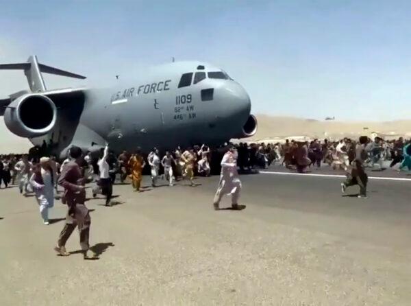 Hundreds of people run alongside a U.S. Air Force C-17 transport plane as it moves down a runway of the international airport, in Kabul, Afghanistan, on Aug. 16, 2021. (Verified UGC via AP)