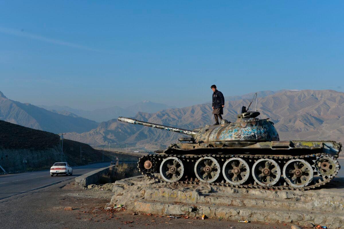 An Afghan boy plays on the wreckage of a Soviet-era tank alongside a road on the outskirts of Kabul on Nov. 28, 2019. (Noorullah Shirzada/AFP via Getty Images)