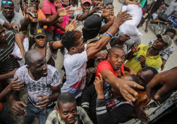 Earthquake victims scramble for a handout of rice at a food distribution place in Les Cayes, Haiti, on Aug. 16, 2021. (Joseph Odelyn/AP Photo)