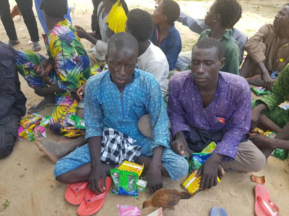 In an undated photo provided by the Nigerian army, former members of Boko Haram sit with snacks provided by the army at a location near Maiduguri, Nigeria. (courtesy Nigerian army)