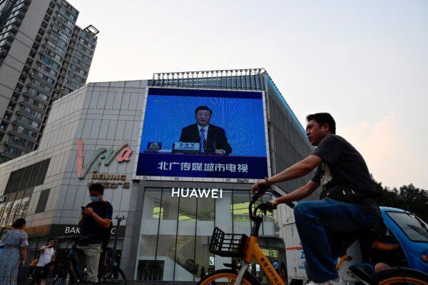 A screen shows news coverage of Chinese leader Xi Jinping delivering a speech during a Chinese Communist Party and World Political Parties summit, as people walk outside a shopping mall in Beijing on July 7, 2021. (Jade Gao/AFP via Getty Images)