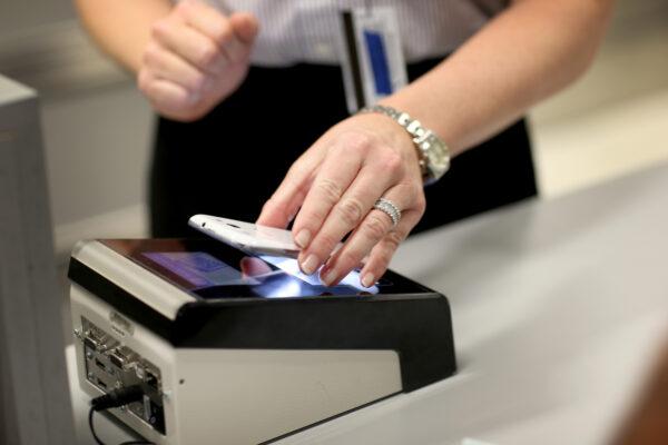 A person passes her smartphone over a scanner as she uses the new mobile app for expedited passport and customer screening being unveiled for international travelers arriving at Miami International Airport in Miami, Fla., on March 4, 2015. (Joe Raedle/Getty Images)