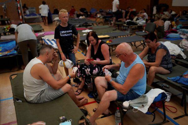 Evacuated campers play cards in a gymnasium in Bormes-les-Mimosas, southern France, on Aug. 18, 2021. (Daniel Cole/AP Photo)