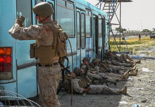 U.S. soldiers rest as Afghan people nearby wait to leave the Kabul airport in Kabul on Aug. 16, 2021. (Wakil Kohsar/AFP via Getty Images)