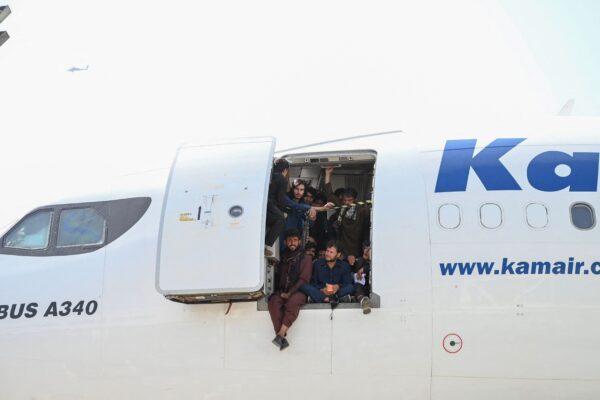 Afghan people climb up on a plane and sit by the door as they wait at the Kabul airport in Kabul on Aug. 16, 2021. (Wakil Kohsar/AFP via Getty Images)