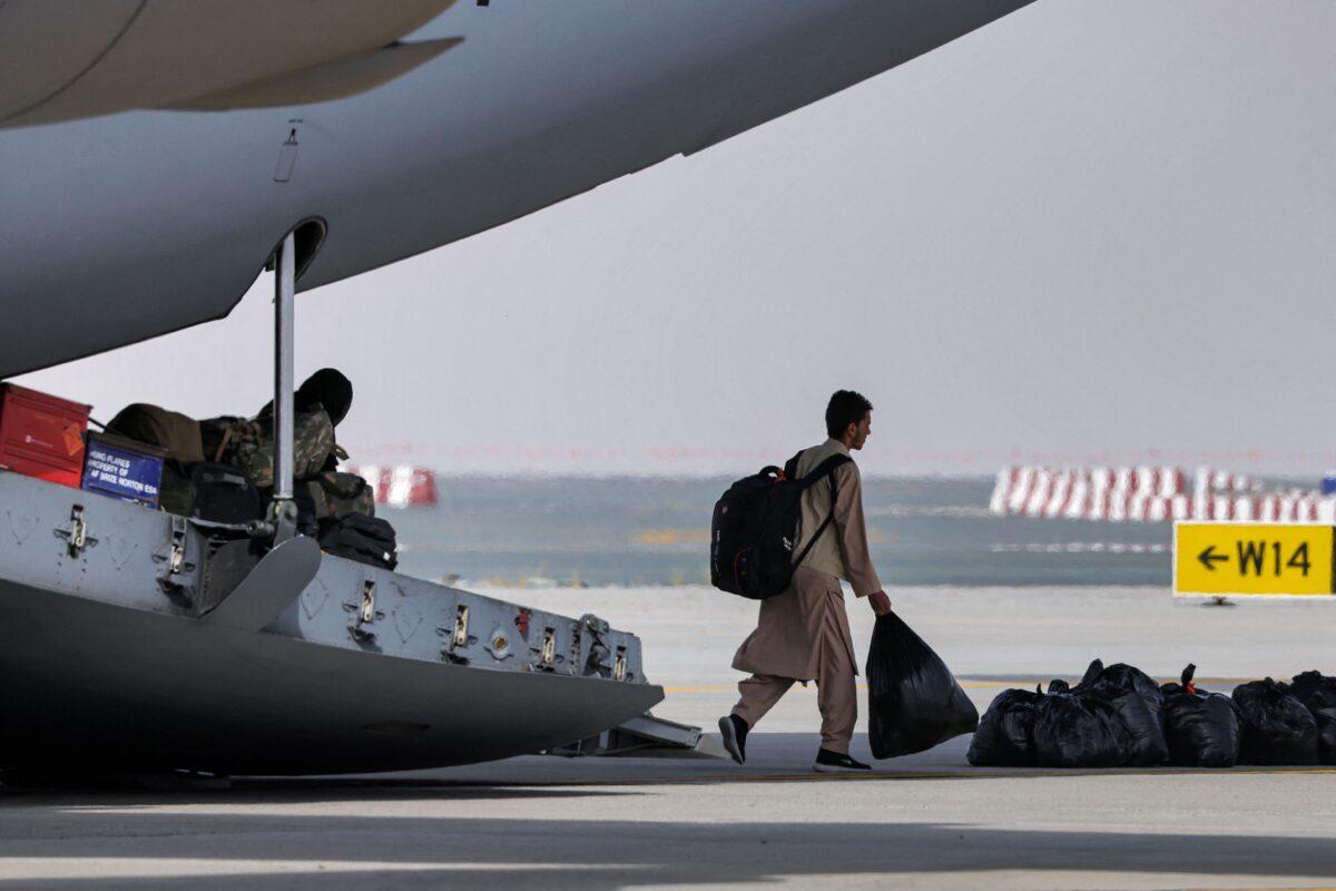 People disembark an RAF military transport aircraft carrying evacuees from Afghanistan International Airport in Dubai which is serving as a staging post on the way to the UK on Aug. 19, 2021 (Giuseppe Cacace/AFP via Getty Images)