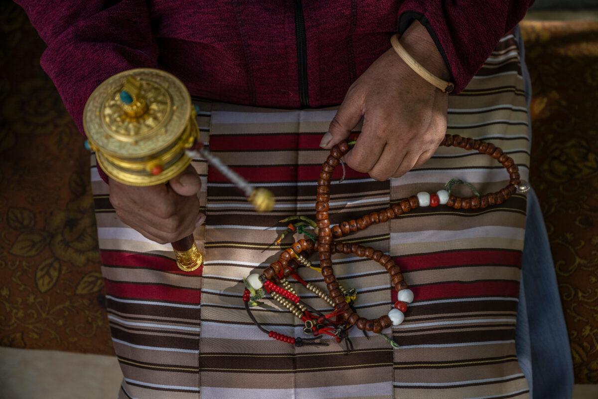 A Tibetan Buddhist woman holds prayer beads as he spins a prayer wheel at a local shrine in Lhasa, Tibet, China, on June 3, 2021. (Kevin Frayer/Getty Images)