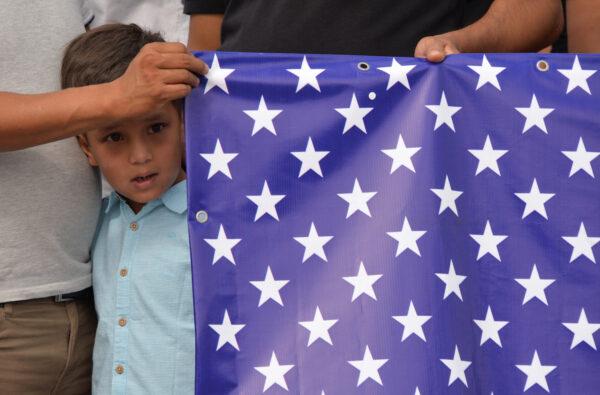 Afghan refugees, who fled Afghanistan in 1996, hold a U.S. flag as they attend a rally in front of the U.S. Embassy in Bishkek, on Aug. 19, 2021. (Vyacheslav Oseledko/AFP)