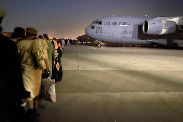 Afghan people queue up to board a U.S. military aircraft to leave Afghanistan at the military airport in Kabul on Aug. 19, 2021, after the Taliban's takeover of Afghanistan. (Shakib Rahmani/AFP via Getty Images)