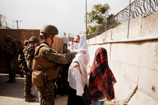 Two civilians during processing through an evacuee control checkpoint during an evacuation at Hamid Karzai International Airport, in Kabul, Afghanistan, on Aug. 18, 2021. (Staff Sgt. Victor Mancilla/U.S. Marine Corps via AP)