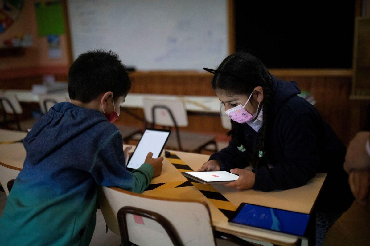 Diego Guerrero, 7, and Sofia Diaz, 7, connect to the internet through Starlink's satellite antenna at the John F. Kennedy School in the village of Sotomo, outside the town of Cochamo, Los Lagos region, Chile, on Aug. 6, 2021. (Pablo Sanhueza/Reuters)