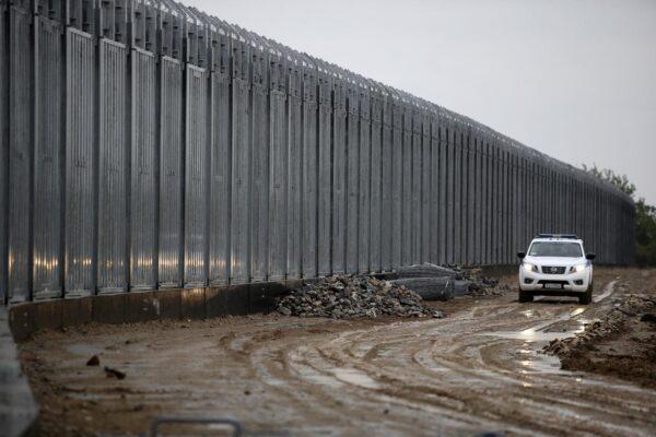A police car patrols alongside a steel wall at Evros river, near the village of Poros, at the Greek-Turkish border, Greece, on May 21, 2021. (Giannis Papanikos/AP Photo)