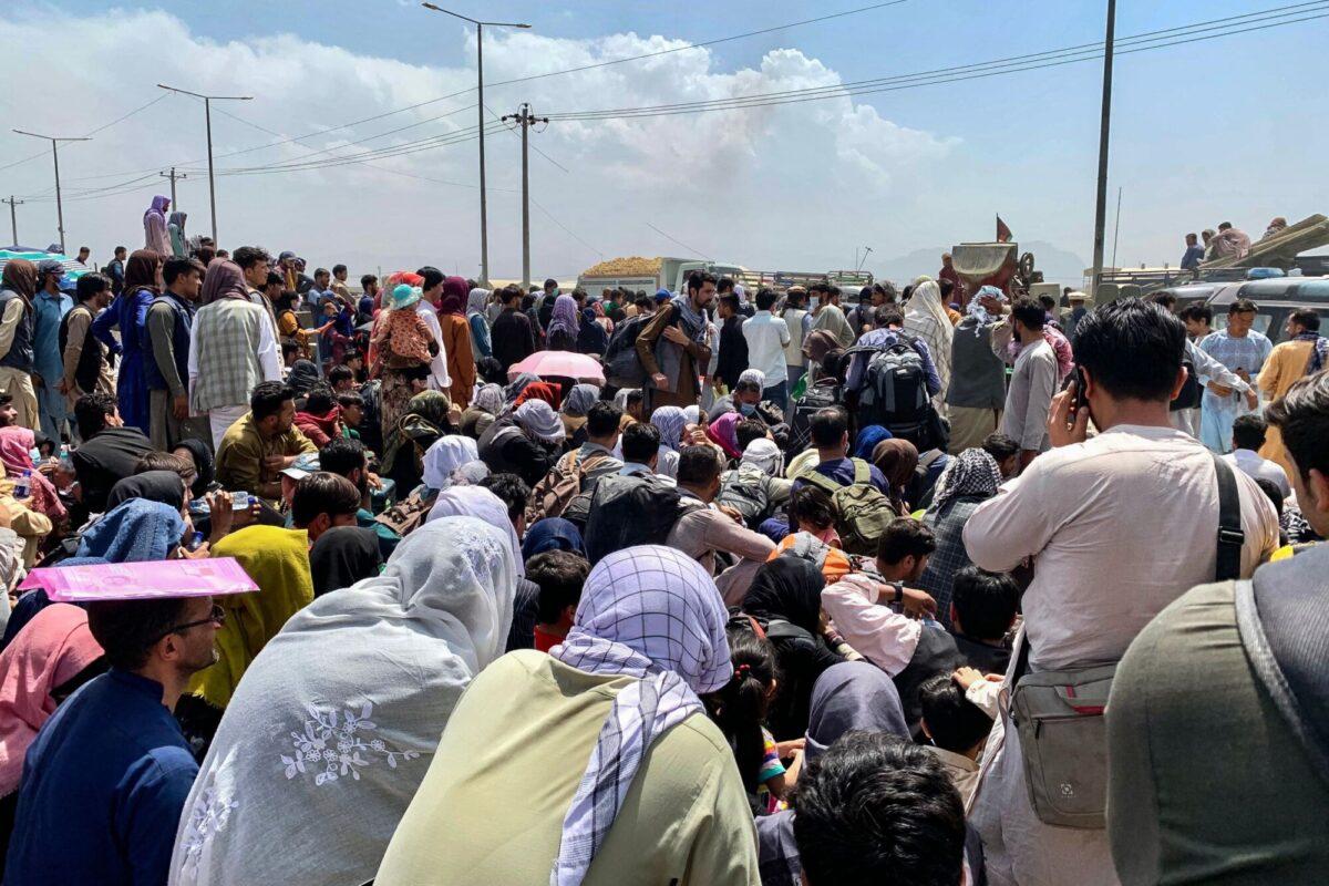 Afghan people gather along a road as they wait to board a U.S. military aircraft to leave the country, at a military airport in Kabul, Afghanistan, on Aug. 20, 2021. (Wakil Kohsar/AFP via Getty Images)