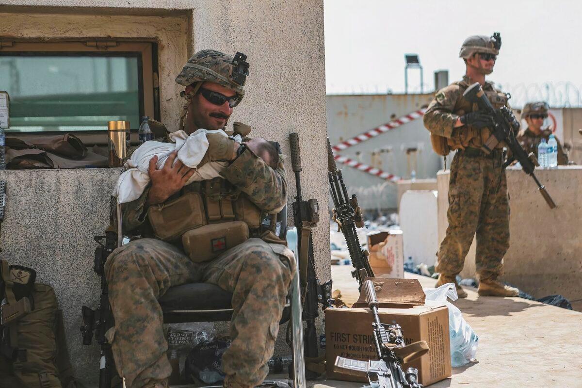 A Marine assigned to the 24th Marine Expeditionary Unit (MEU) calms an infant during an evacuation at Hamid Karzai International Airport, in Kabul, Afghanistan, on Aug. 20, 2021. (Sgt. Isaiah Campbell/U.S. Marine Corps via AP)