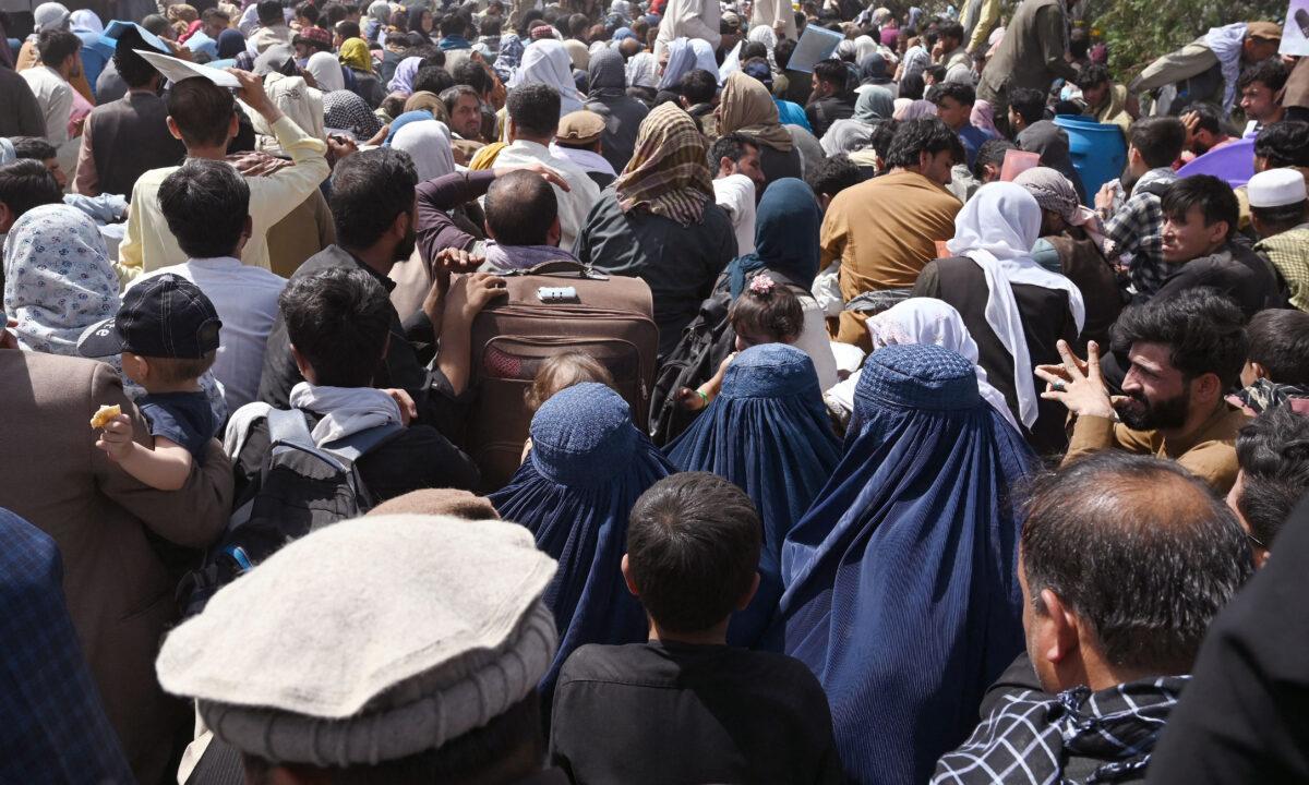 Afghans gather on a roadside near the military part of the airport in Kabul, hoping to flee from the country after the Taliban's military takeover of Afghanistan, in Kabul, Afghanistan, on Aug. 20, 2021. (Wakil Kohsar/AFP via Getty Images)