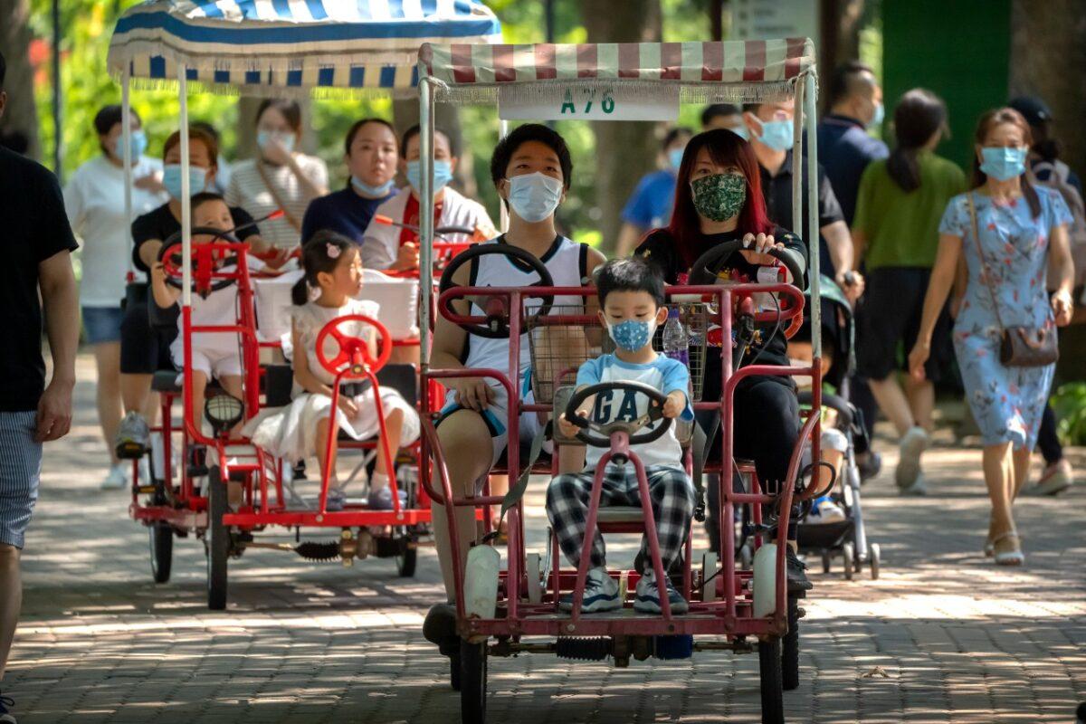 Adults and children ride pedal cycles at a public park in Beijing, on Aug. 21, 2021. China will now allow couples to have a third child as the country seeks to hold off a demographic crisis that threatens its hopes of increased prosperity and global influence. (Mark Schiefelbein/AP Photo)