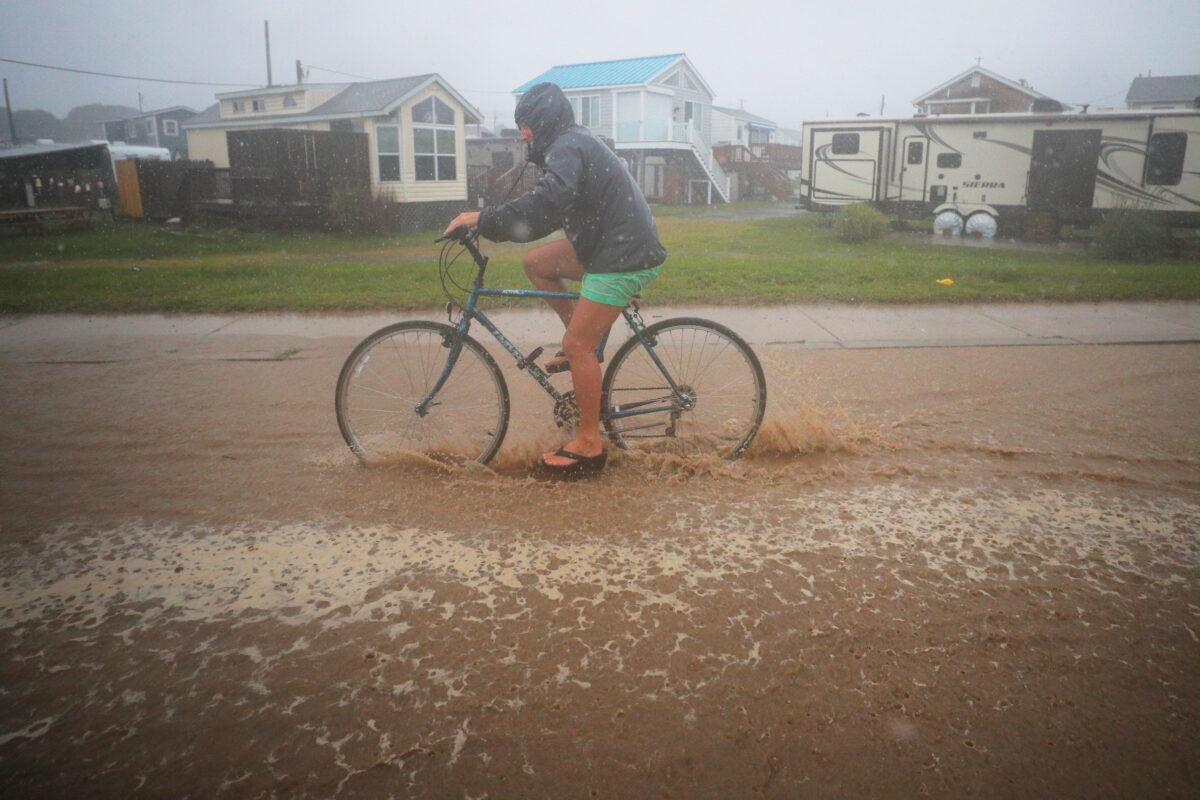 A bicyclist rides through a flooded street as Tropical Storm Henri approaches South Kingstown, R.I., U.S., August 22, 2021. REUTERS/Brian Snyder