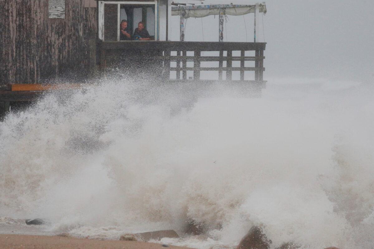 People watch as the waves crash around the Ocean Mist bar as Tropical Storm Henri approaches South Kingstown, R.I., on. Aug. 22, 2021. (Brian Snyder/Reuters)