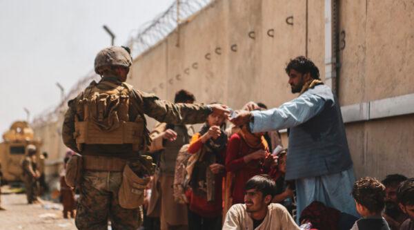 A Marine with the 24th Marine Expeditionary unit passes out water to evacuees during the evacuation at Hamid Karzai International Airport in Kabul, Afghanistan, on Aug. 21, 2021. (Isaiah Campbell/U.S. Marine Corps via Getty Images)