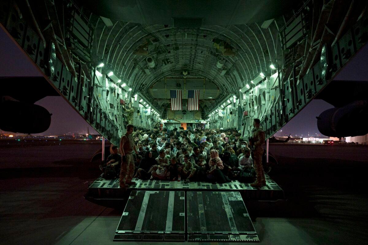 U.S. Air Force aircrew, assigned to the 816th Expeditionary Airlift Squadron, assist qualified evacuees boarding a U.S. Air Force C-17 Globemaster III aircraft in support of the Afghanistan evacuation at Hamid Karzai International Airport, Kabul, Afghanistan, on Aug. 21, 2021. (Senior Airman Taylor Crul/U.S. Air Force via AP)