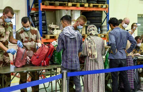 People have their luggage checked by soldiers in a reunion and evacuation center at the French military airbase 104 of Al Dhafra, near Abu Dhabi, on Aug. 23, 2021, after being evacuated from Kabul as part of the operation "Apagan". (Bertrand Guay/AFP via Getty Images)