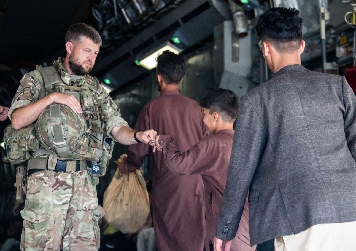 Handout photo issued by the Ministry of Defence (MoD) of a member of the UK Armed Forces fist-bumping a child evacuee at Kabul airport. (LPhot Ben Shread/MoD via PA)