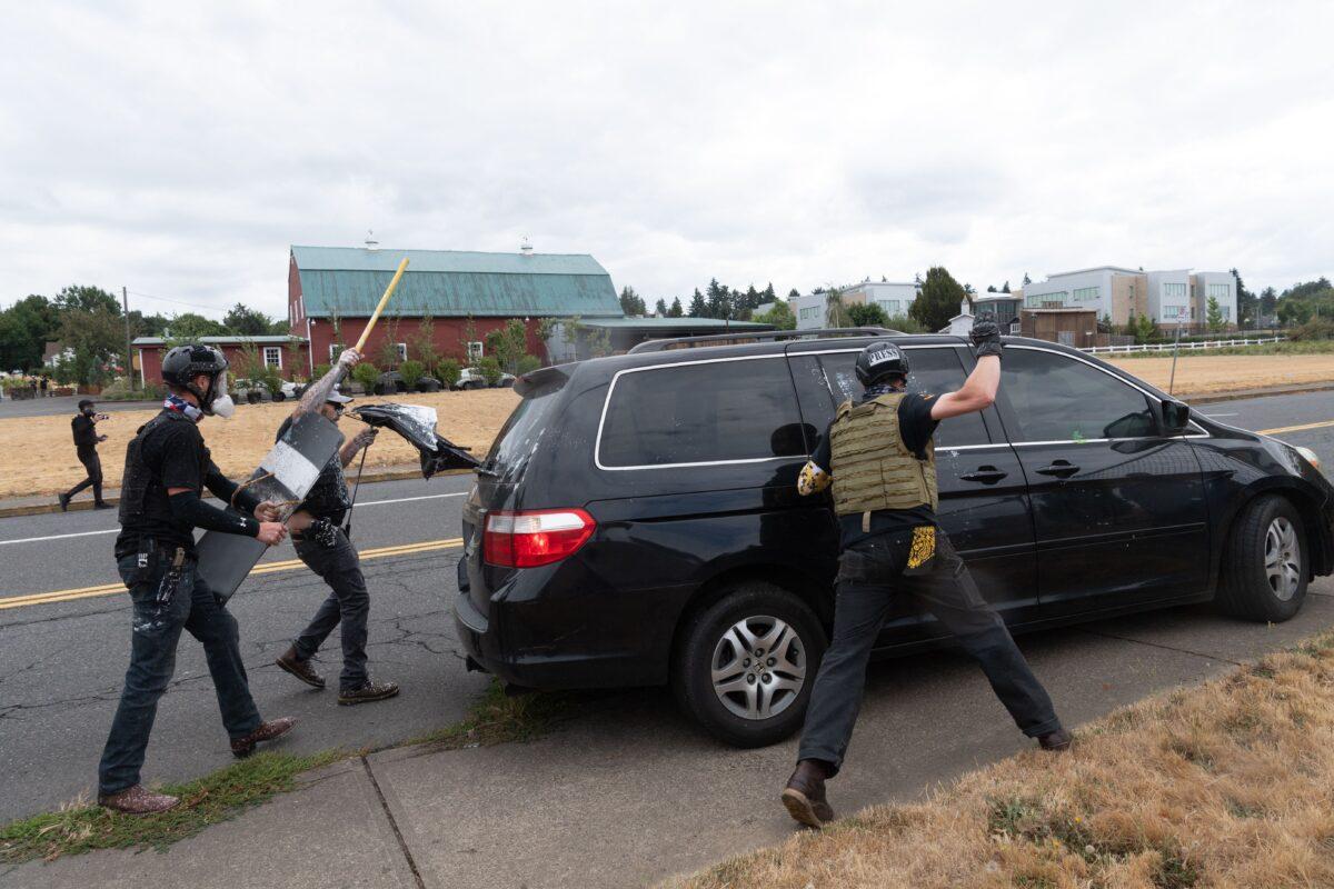 Members of the Proud Boys attack a van during a clash with Antifa members in Portland, Ore., on Aug. 22, 2021. (Mathieu Lewis-Rolland/AFP via Getty Images)