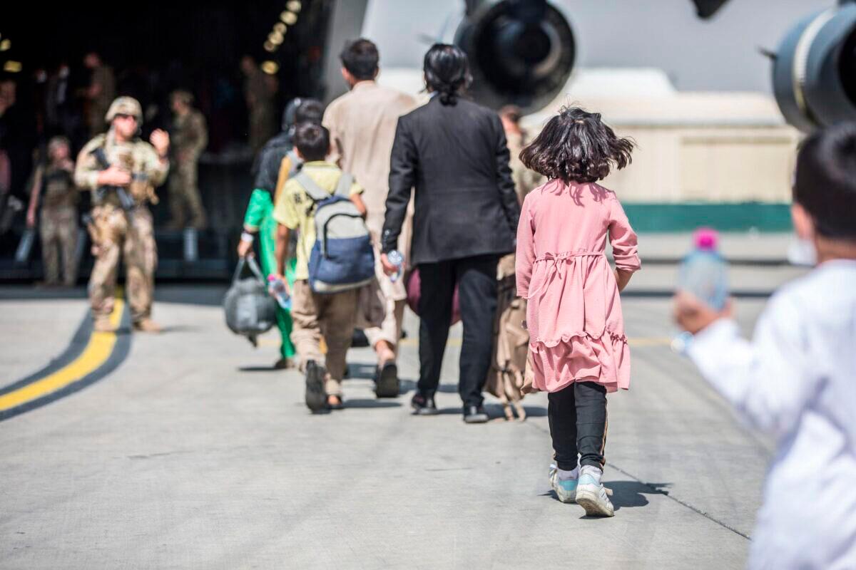Families begin to board a U.S. Air Force C-17 Globemaster III transport plane during an evacuation at Hamid Karzai International Airport, Afghanistan, on Aug. 23, 2021. (U.S. Marine Corps/Sgt. Samuel Ruiz/Handout via Reuters)