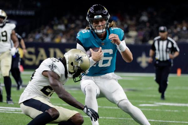 Jacksonville Jaguars quarterback Trevor Lawrence (16) tries to avoid a hit by New Orleans Saints cornerback Paulson Adebo in the first half of an NFL preseason football game in New Orleans, La., on Aug. 23, 2021. (Derick Hingle/AP Photo)