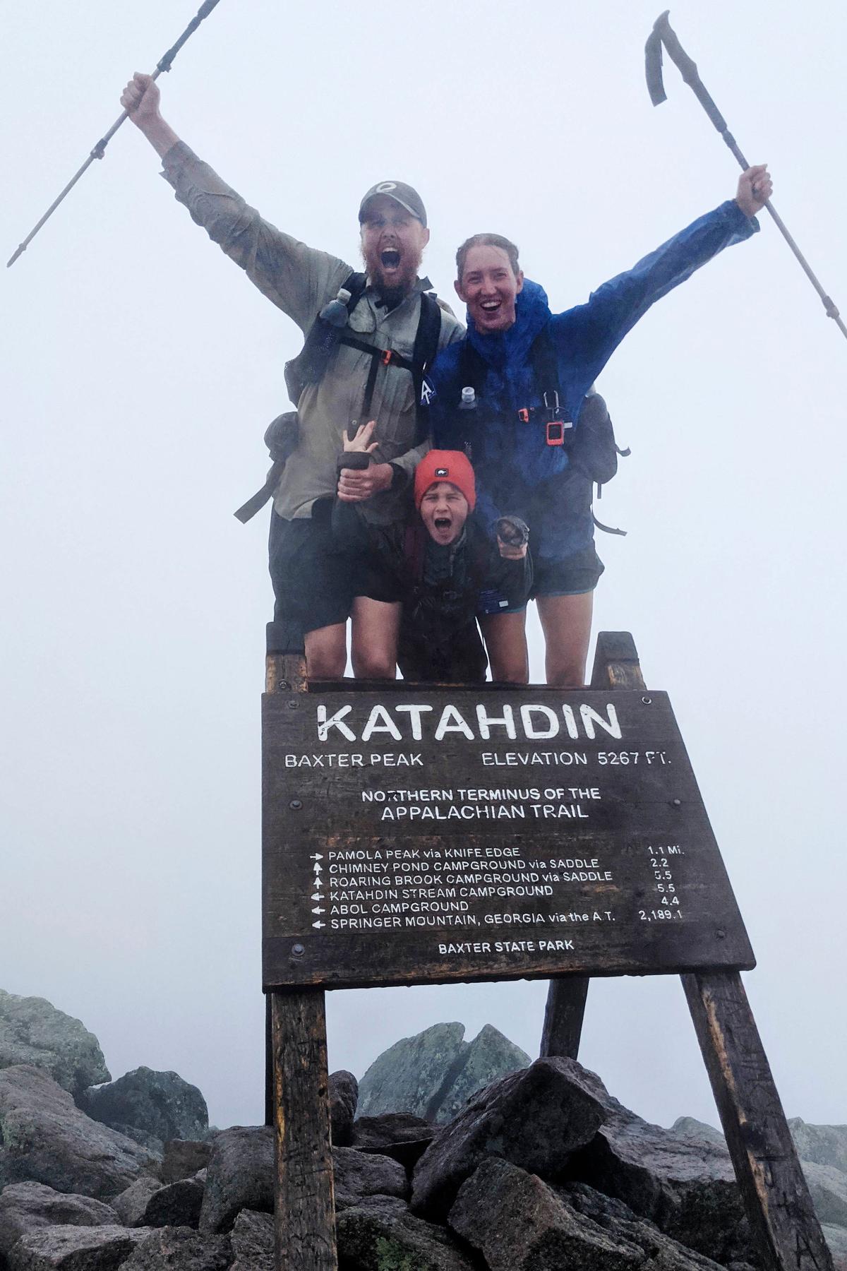 Harvey Sutton (C) poses with his mom, Cassie (R), and dad, Joshua, at the summit of Mount Katahdin, Maine, on Aug. 9, 2021, while hiking the Appalachian Trail with his mom and dad. (Joshua Sutton/AP Photo)