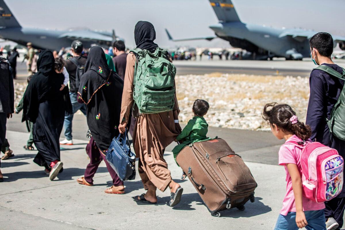 A child looks at the aircraft as he is strolled towards his flight during an evacuation at Hamid Karzai International Airport, Kabul, Afghanistan, Aug. 24, 2021. (Sgt. Samuel Ruiz/U.S. Marine Corps via AP)