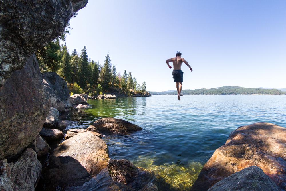A young man jumps off a rocky cliff in Tubbs Hill. (Nature's Charm/Shutterstock)
