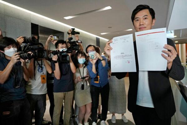 Lawmaker Cheng Chung-Tai displays a document as he is surrounded by reporters after being disqualified from the legislature in Hong Kong, on Aug. 26, 2021. (Vincent Yu/AP Photo)
