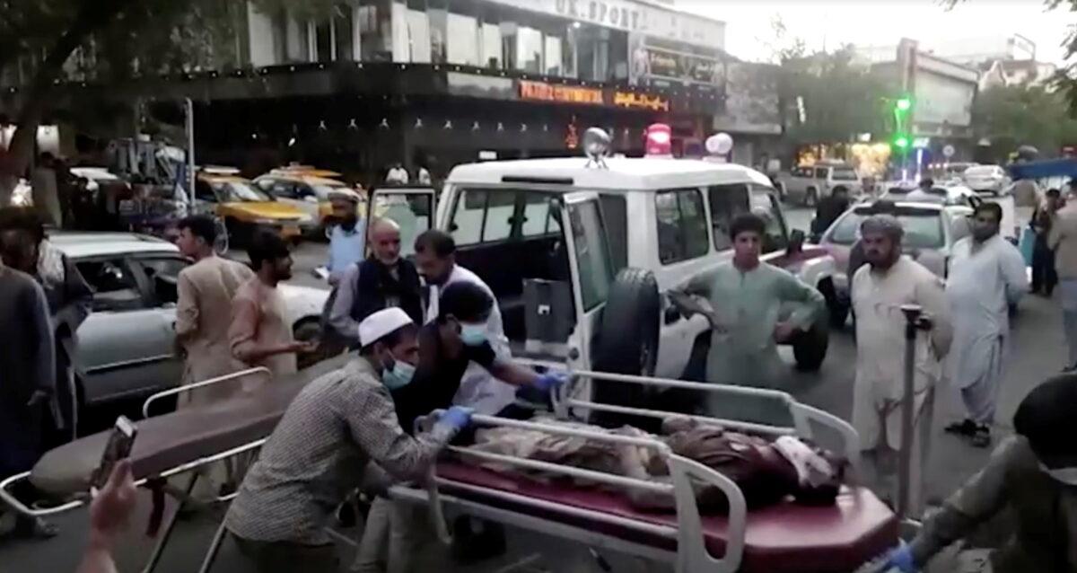 A screengrab shows people carrying an injured person to a hospital after an attack at Kabul airport, in Kabul, Afghanistan on Aug. 26, 2021. (Reuters TV/1TV via Reuters)
