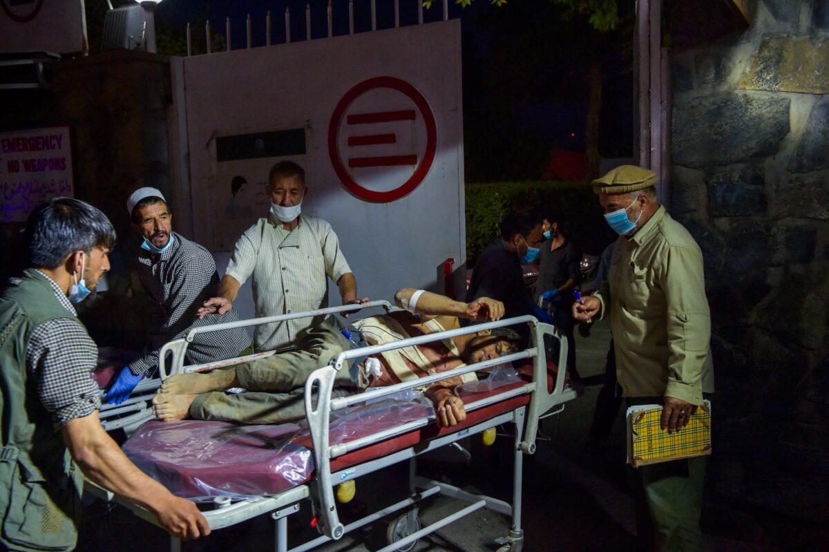 Medical and hospital staff bring an injured man on a stretcher for treatment after explosions in Kabul, Afghanistan on Aug. 26, 2021. (Wakil Kohsar/AFP via Getty Images)