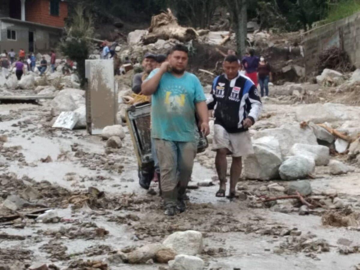 People walk on the street covered in mud following flash flooding in Tovar, Merida State, Venezuela, on Aug. 25, 2021. (Courtesy of Comunicacion Continua/ comunicacioncontinua.com/ Handout via Reuters)