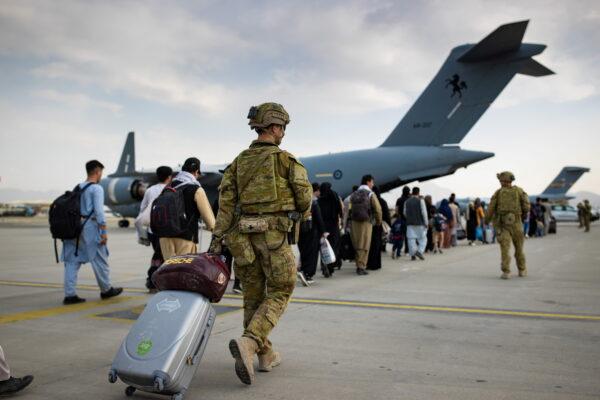Australian citizens and visa holders prepare to board the Royal Australian Air Force C-17A Globemaster III aircraft, as Australian Army infantry personnel provide security and assist with cargo, at Hamid Karzai International Airport in Kabul, Afghanistan, on Aug. 22, 2021. (SGT Glen McCarthy/Australia's Department of Defence/Handout via Reuters)