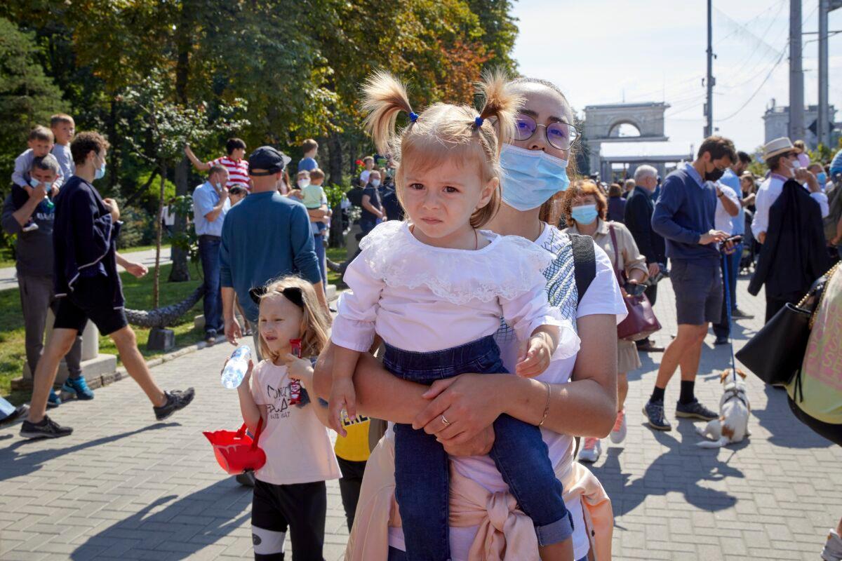 A woman holds a baby before a military parade held to celebrate Moldova's national day, three decades after the country declared independence from the Soviet Union, in Chisinau, Moldova, on Aug. 27, 2021. (Aurel Obreja/AP Photo)