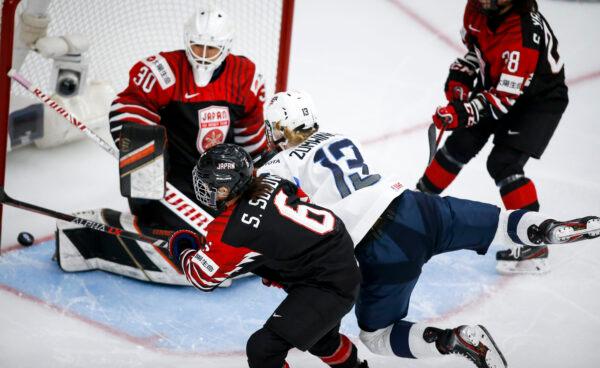 Grace Zumwinkle (13), of the United States, scores against Japan goalie Akane Konishi, left, as she is checked by Japan's Sena Suzuki during third-period quarterfinal IIHF women's world championship hockey game action in Calgary, Alberta, on Aug. 28, 2021. (Jeff McIntosh/The Canadian Press via AP)